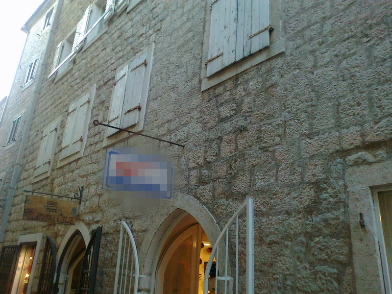 Fassade eines historischen Steingebäudes mit Holzläden in der Altstadt von Budva, Montenegro.