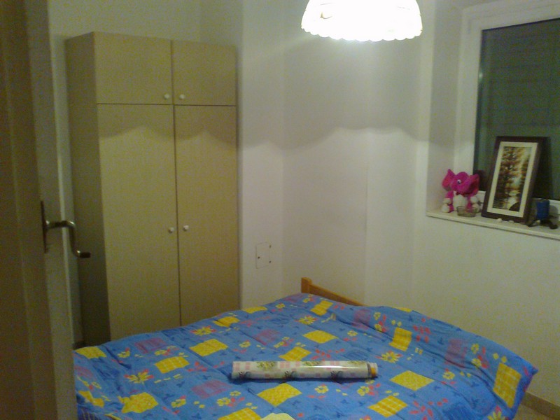 Gemütliches Schlafzimmer in einer Wohnung in Budva, Montenegro: Doppelbett, heller Kleiderschrank, Fenster mit Dekoration und Lampe.