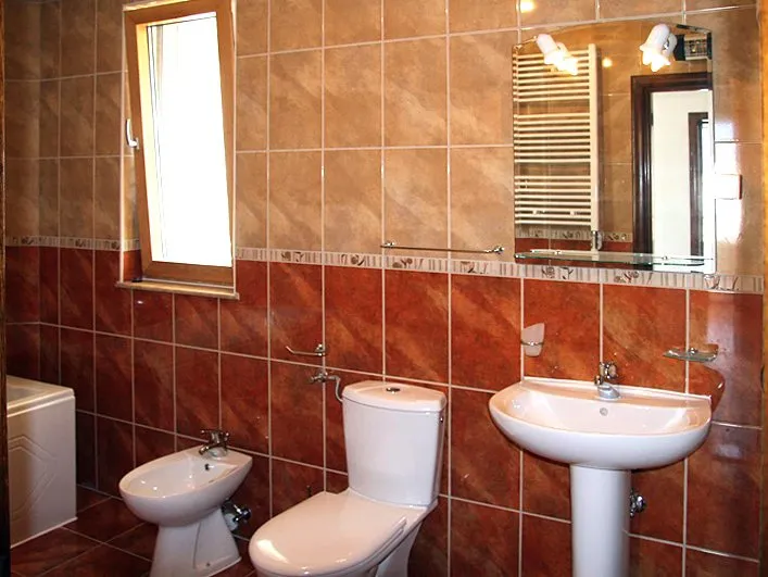 Badezimmer mit weißer Sanitärkeramik und Fliesenverkleidung in einem Haus zum Verkauf in Krašići, Montenegro.