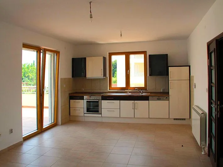 Moderne Küche mit Möbeln und Zugang zur Terrasse im Haus, Krašići, Montenegro. Helles Interieur mit Fliesenboden.