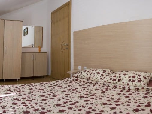 Bedroom in an apartment in Zelenika, Montenegro: a double bed, light wooden furniture, and a mirror on the wall.