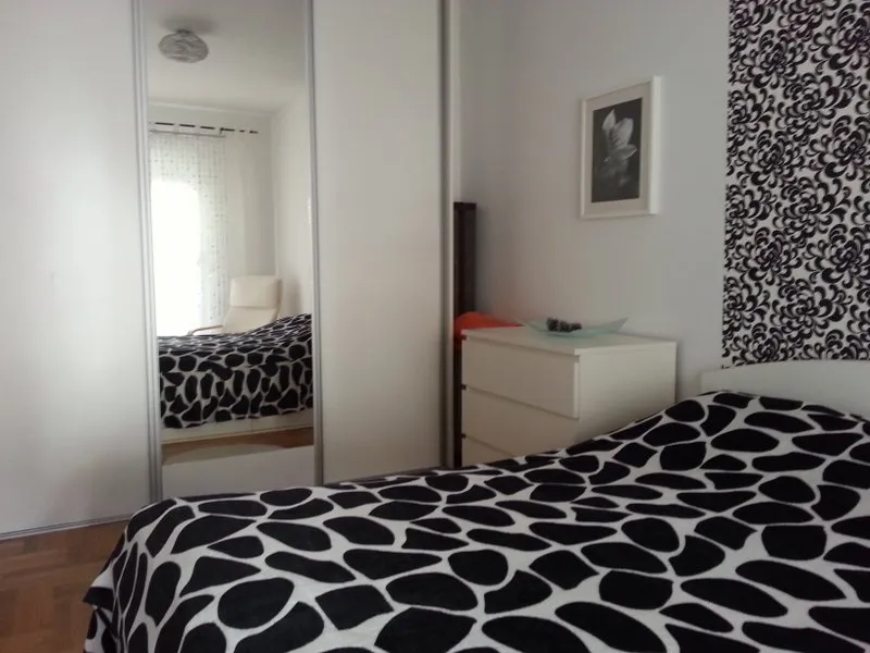 Schlafzimmer in einer Wohnung in Budva, Montenegro: Doppelbett, weißer Kleiderschrank mit Spiegel und Kommode im modernen Stil.