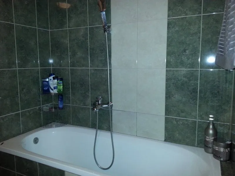 Badezimmer in einer Wohnung in Budva, Montenegro: weiße Badewanne und Wandverkleidung mit grünen Keramikfliesen.