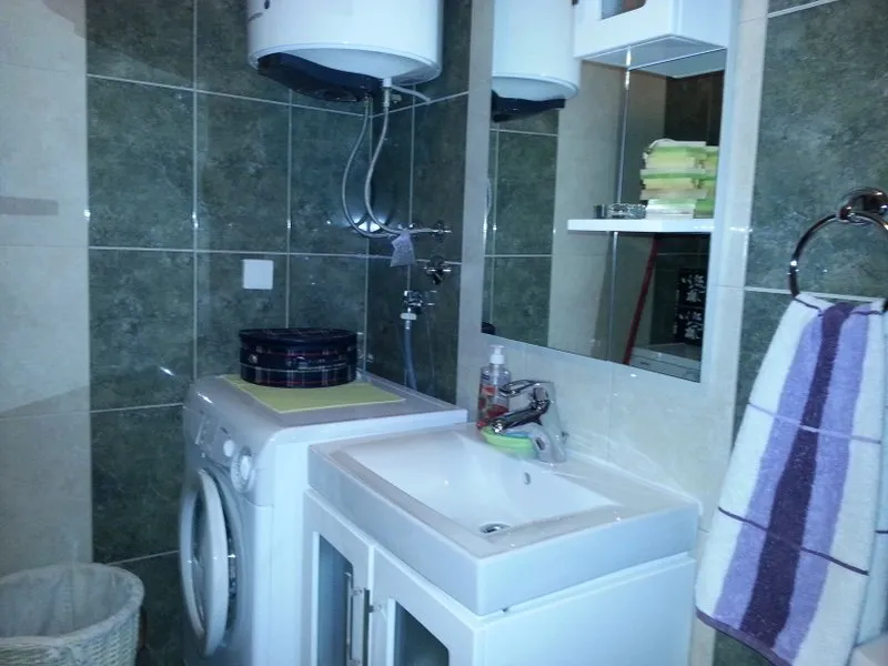 Badezimmer in einer Wohnung in Budva, Montenegro: Waschbecken mit Unterschrank, Waschmaschine und Boiler, gefliest.