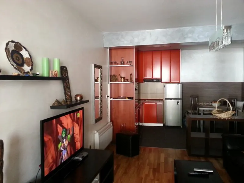 Wohnzimmer mit Küche in einer Wohnung in Budva, Montenegro: rote Küchenfronten, Essbereich und TV-Bereich mit Dekor.