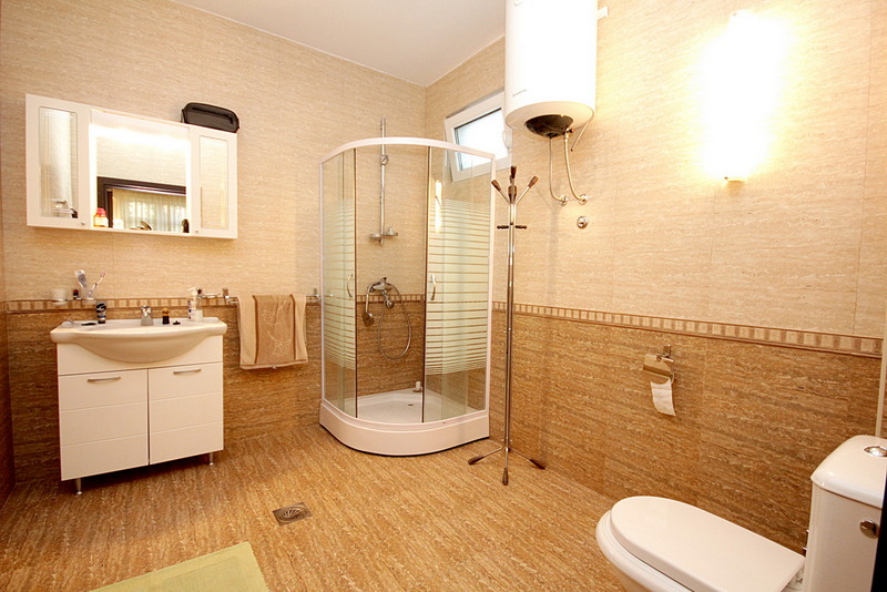 Ein kompaktes, modernes Badezimmer mit Duschkabine, Waschbeckenunterschrank und Toilette.