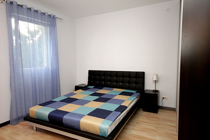 Schlafzimmer mit Doppelbett, Nachttischen und einem Fenster.