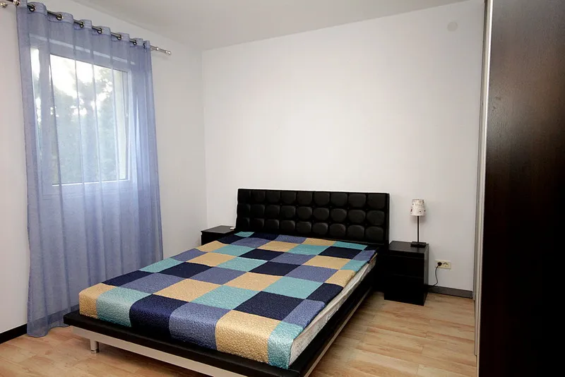Schlafzimmer mit Doppelbett, Nachttischen und einem Fenster.