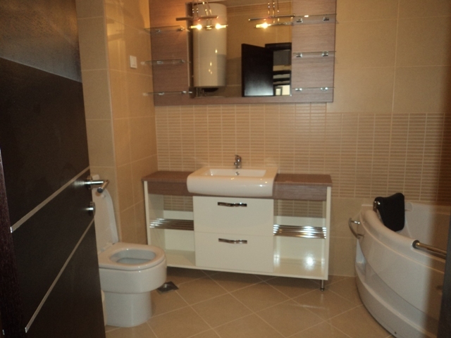 Modernes Badezimmer in einer Wohnung in Bečići, Montenegro: Eckbadewanne, Waschtisch mit Waschbecken und Spiegel.