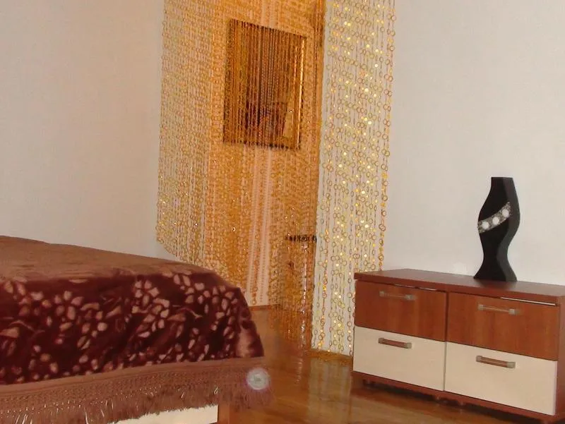 Schlafzimmerinterieur in einer Wohnung in Budva, Montenegro: Doppelbett, Kommode und dekorativer Vorhang aus goldenen Perlen.