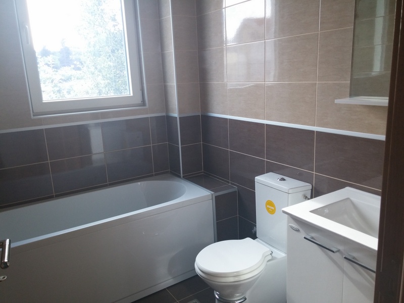 Savremeno kupatilo sa pločicama, kadom i sanitarnom opremom u kući na prodaju u Đenovićima, Crna Gora.