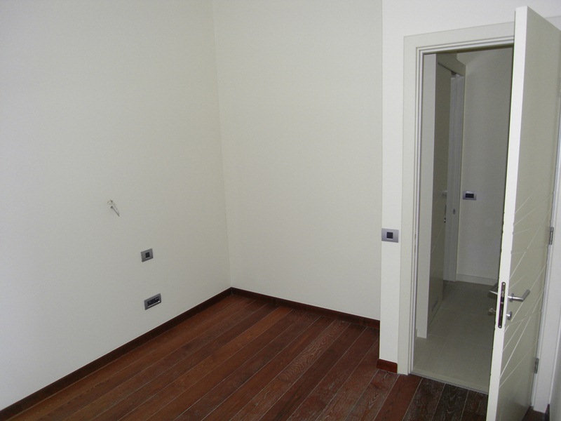 Helles Schlafzimmer mit Parkettboden und Innentür in einer Wohnung in Budva, Montenegro. Moderne Innenausstattung.