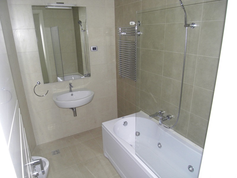 Modernes Badezimmer mit Whirlpool und Fliesen in einer Wohnung in Budva, Montenegro. Waschbecken, Bidet und Spiegel sind installiert.