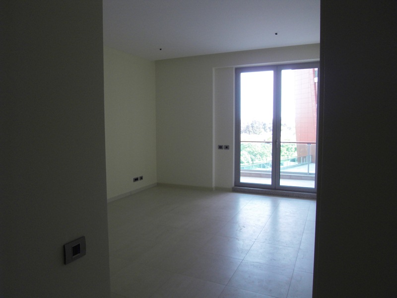 Helles Wohnzimmer in einer Wohnung in Budva, Montenegro: Panoramafenster, Zugang zum Balkon und moderne Fliesenverkleidung.