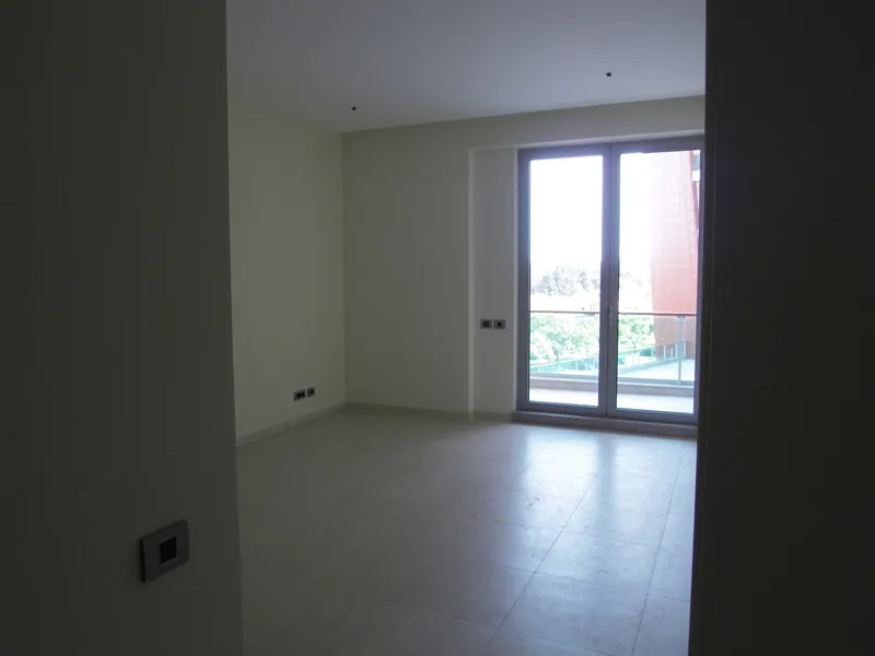 Helles Wohnzimmer in einer Wohnung in Budva, Montenegro: Panoramafenster, Zugang zum Balkon und moderne Fliesenverkleidung.