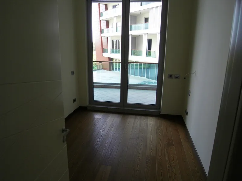 Helles Schlafzimmer mit Parkett und Zugang zur Terrasse in einer modernen Wohnung, Budva, Montenegro.