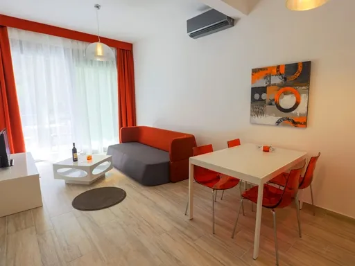 Wohnzimmer mit Sofa, Couchtisch, Essgruppe und Gemälde an der Wand.