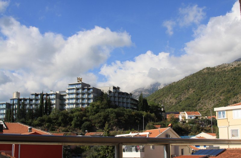 Panoramski pogled sa balkona na hotel, planine i krovove od crepova u naselju Rafailovići, Crna Gora.