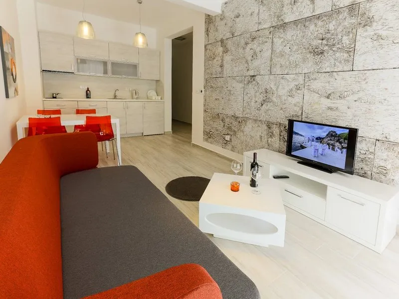 Modernes Wohnzimmer mit orange-grauem Sofa, weißem Couchtisch und TV-Konsole.