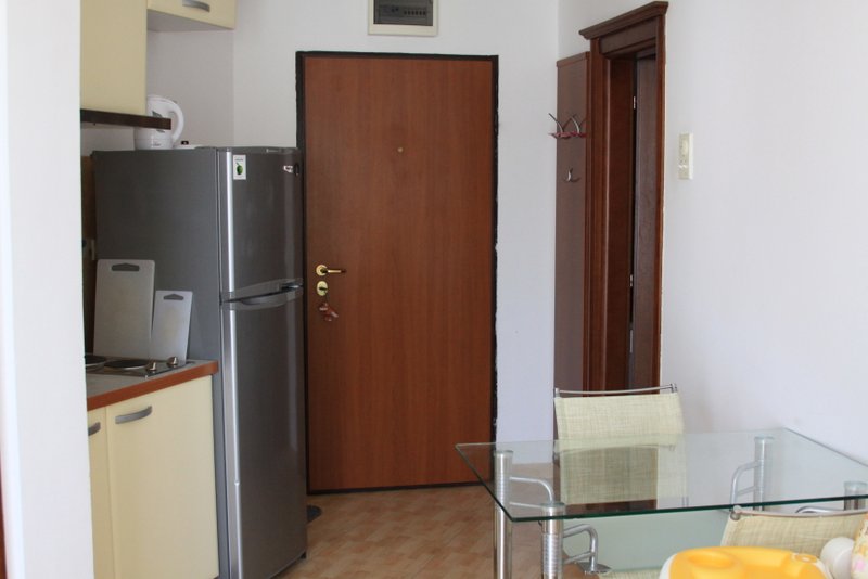 Kuhinja sa trpezarijskim stolom i frižiderom u stanu, Rafailovići, Crna Gora. Enterijer sa drvenim vratima.