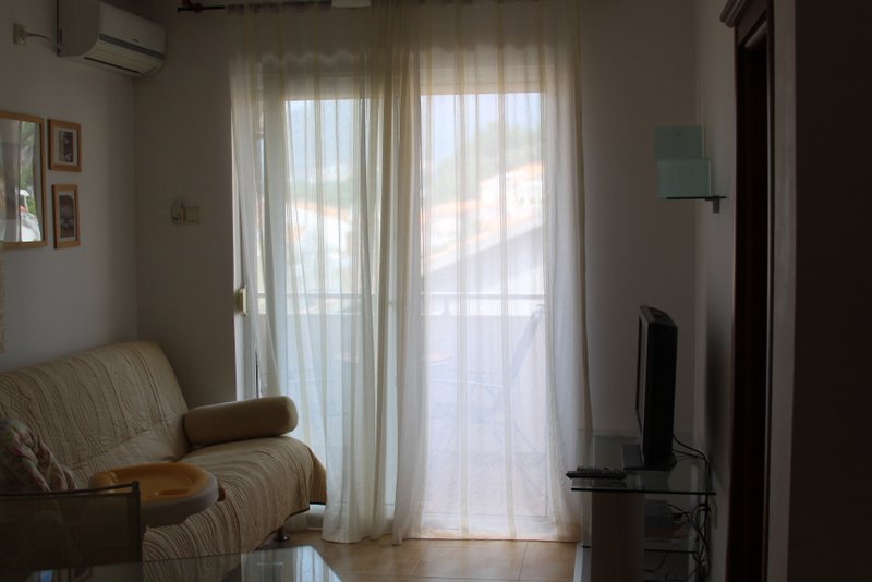Dnevna soba sa sofom i izlazom na balkon u stanu, Rafailovići, Crna Gora. Svetao enterijer sa klima-uređajem.
