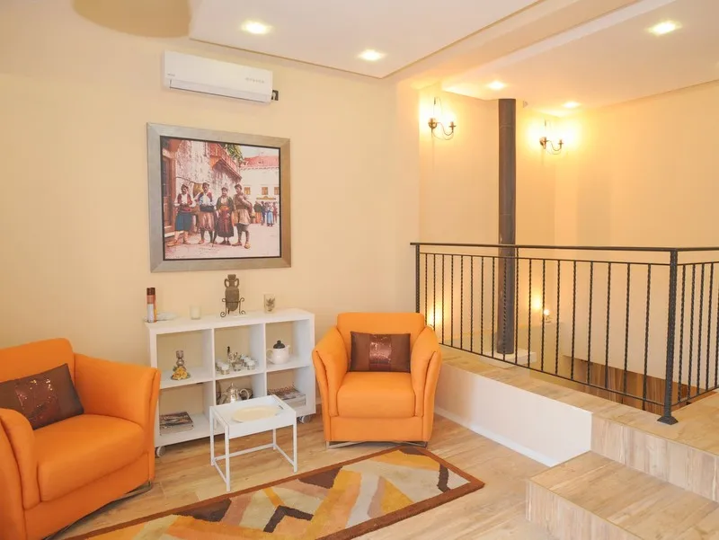 Cozy living room with orange armchairs in a villa in Bigovo, Montenegro: stylish interior, wrought-iron railings, and decor.