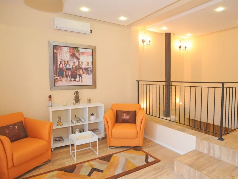 Cozy living room with orange armchairs in a villa in Bigovo, Montenegro: stylish interior, wrought-iron railings, and decor.