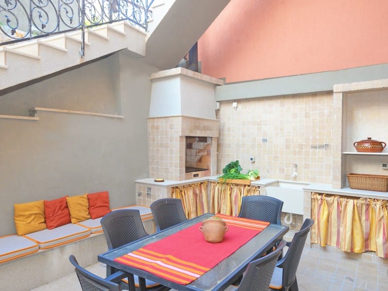 Summer terrace with barbecue and dining area at a villa in Bigovo, Montenegro: stone oven, table, and cushioned seating.