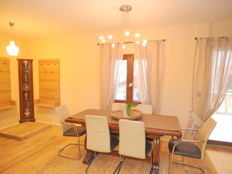 Living room with dining area in a villa in Bigovo, Montenegro: wooden table, light chairs, and a designer chandelier.