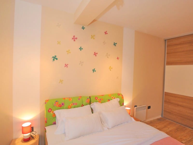 Cozy bedroom with a double bed and a built-in wardrobe in a villa in Bigovo, Montenegro. Bright interior with decor.