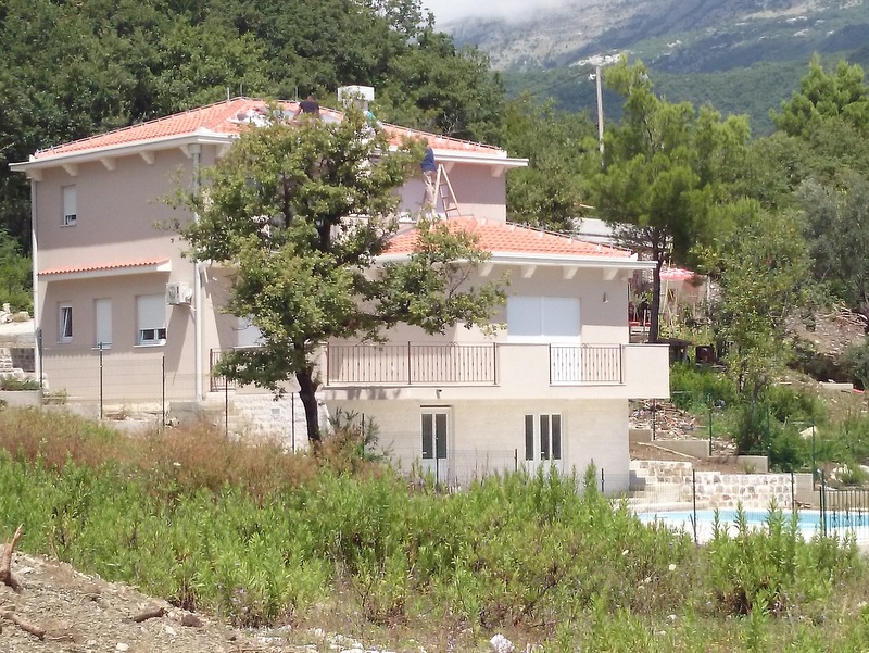 Dvospratna kuća sa krovom od crepa, terasom i bazenom, okružena planinama u Herceg Novom, Crna Gora.