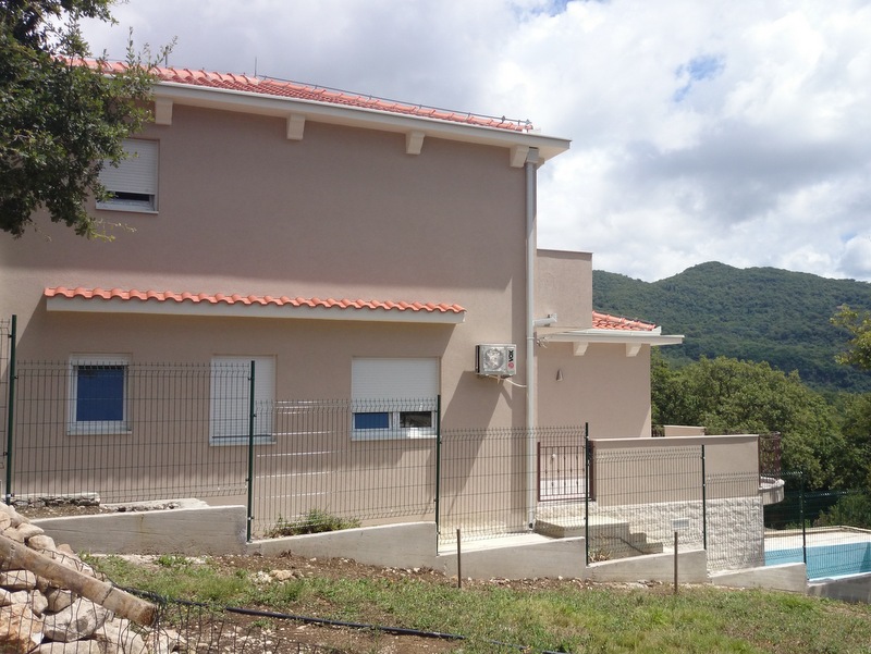 Dvospratna kuća sa krovom od crepa i bazenom u Herceg Novom, Crna Gora, pogled na fasadu i planinski pejzaž.