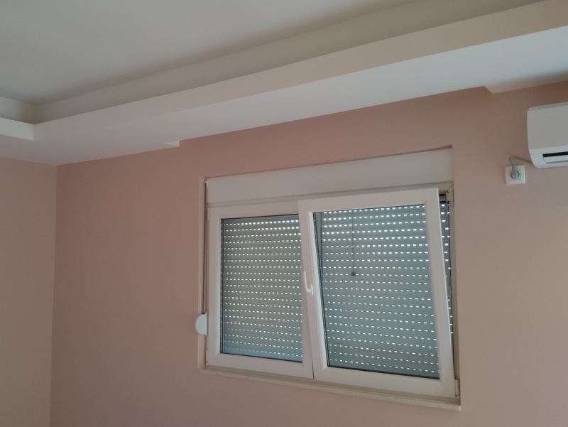 Svetla dnevna soba sa klima-uređajem i prozorom sa zaštitnim roletnama u kući, Herceg Novi, Crna Gora.