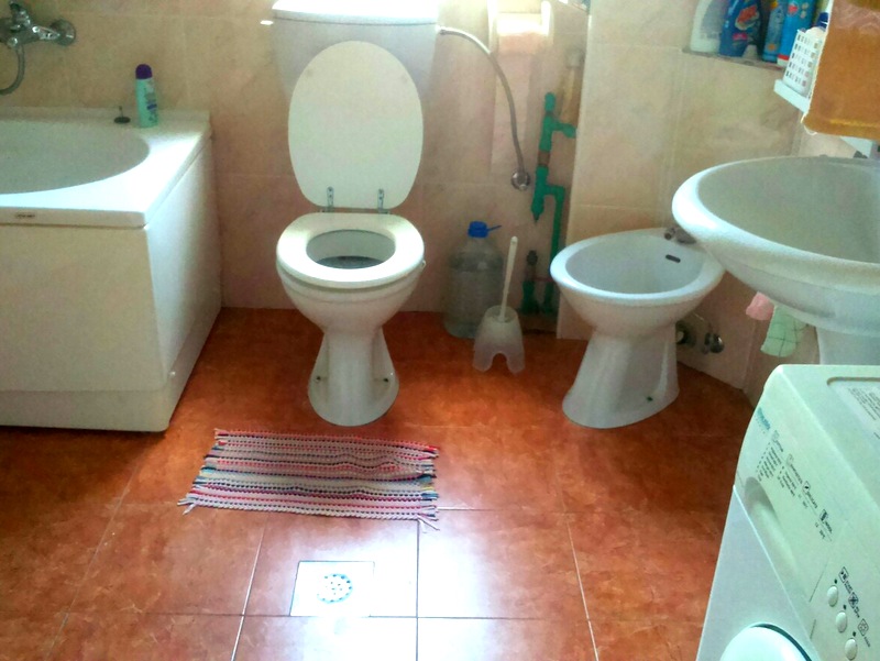 Badezimmer in einer Wohnung in Budva, Montenegro: Fliesen, Badewanne, Toilette, Bidet, Waschbecken und Waschmaschine.