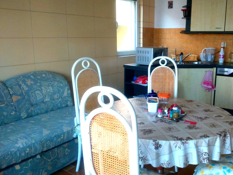 Küche mit Essbereich, Esstisch und Sofa in einer Wohnung in Budva, Montenegro: Innenraum mit Fliesen und Einbauküche.