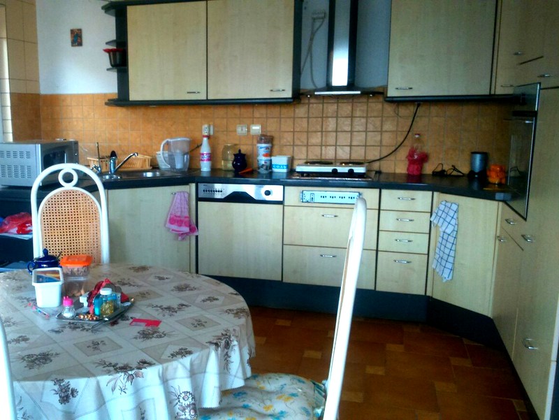 Gemütliche Küche in einer Wohnung in Budva, Montenegro: helle Einbauküche, integrierte Geräte, Essbereich mit Tisch und Stühlen.