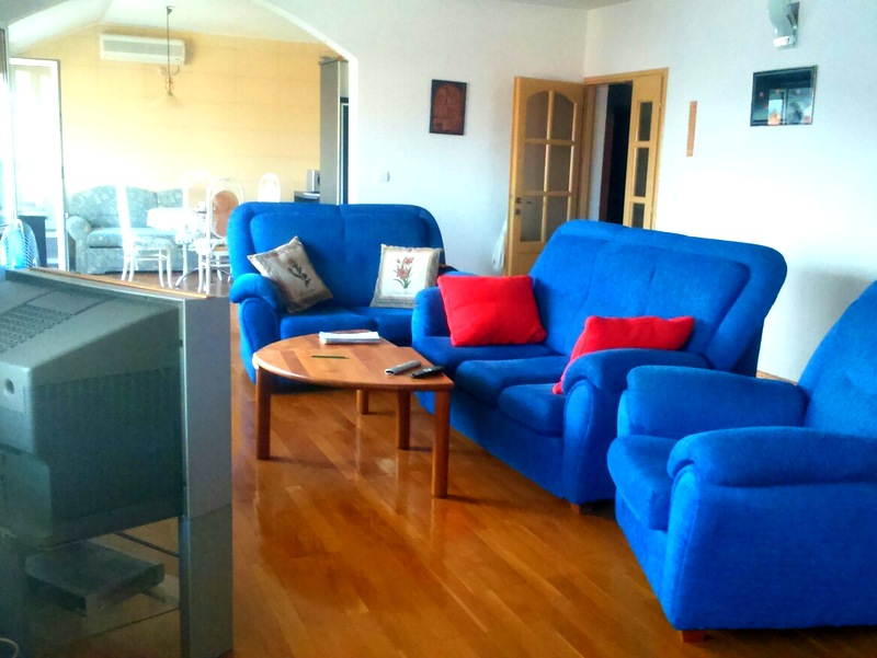 Wohnzimmer mit blauen Polstermöbeln und Holzboden in einer Wohnung zum Verkauf in Budva, Montenegro.