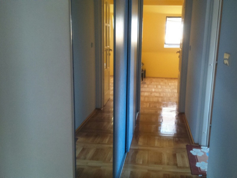 Heller Flur mit Spiegel-Schiebetürschrank und Parkettboden in einer Wohnung, Budva, Montenegro.