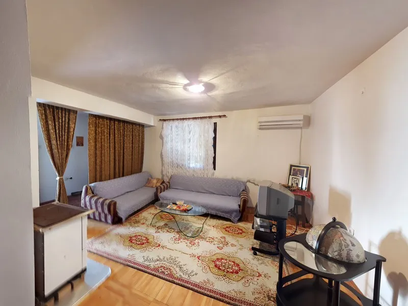 Wohnzimmer in einem Haus in Šušanj, Montenegro: zwei Sofas, ein gemusterter Teppich, ein Ofen und ein Fernseher im Interieur.