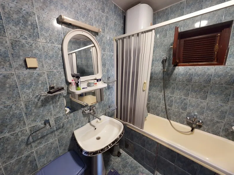 Badezimmer im Haus, Šušanj, Montenegro: Fliesen in Blautönen, Waschbecken, Badewanne mit Vorhang und Boiler.