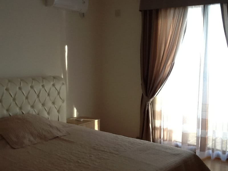 Bedroom in a house in Shushan, Montenegro: a double bed with a soft headboard, a bright interior, and access to the balcony.