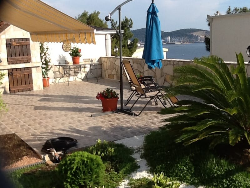 House terrace in Shushan, Montenegro: stone grill, sun loungers, awning, and panoramic sea and mountain views in the garden.