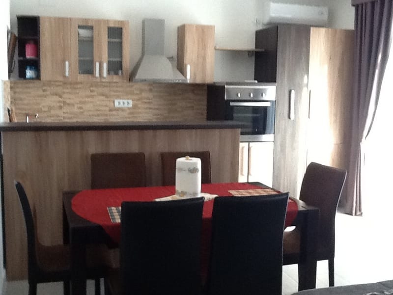 Modern kitchen with dining area in a house, Shushan, Montenegro: wooden cabinets, built-in appliances, and a table.