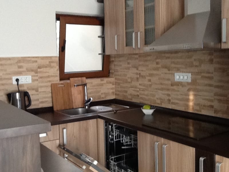 Modern kitchen in a house in Shushan, Montenegro: wooden fronts, built-in appliances, and a sink by the window.