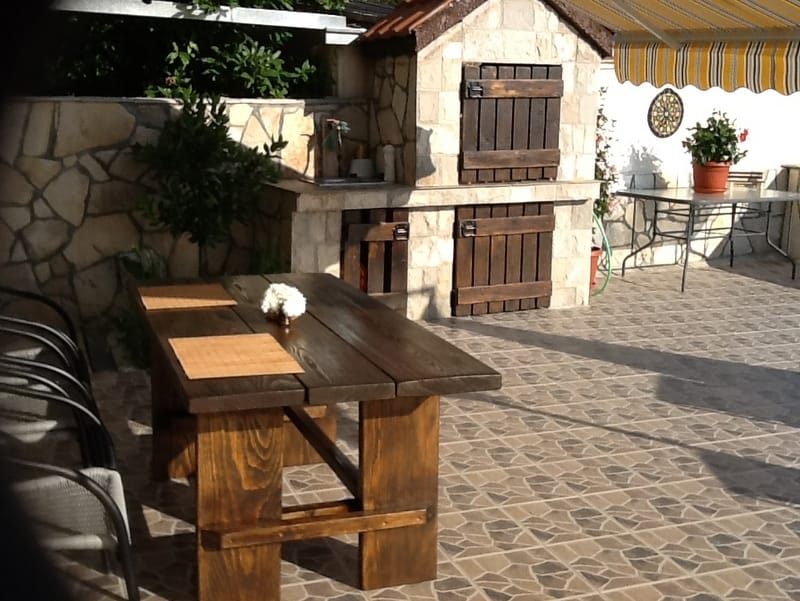 Terrace with a stone barbecue and a wooden table in a house in Shushan, Montenegro. Outdoor relaxation area.