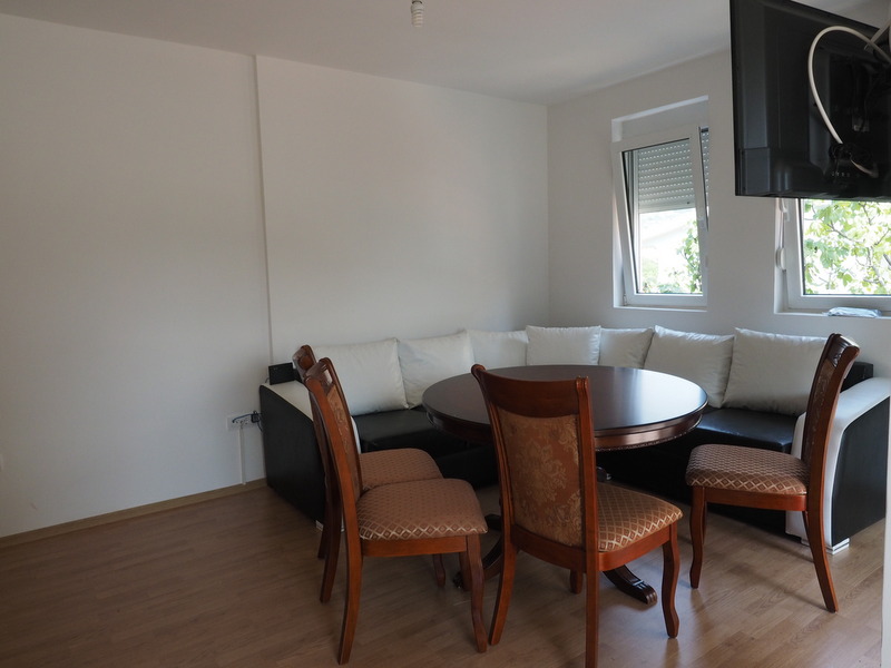 Wohnzimmer mit Essbereich und Ecksofa in einer Wohnung in Šušanj, Montenegro: Innenraum mit Holztisch und Stühlen.