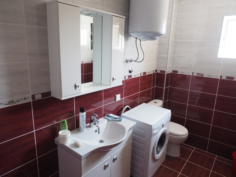 Badezimmer in der Wohnung, Shushan, Montenegro: Fliesen, Waschbecken mit Unterschrank, Spiegel und Waschmaschine.