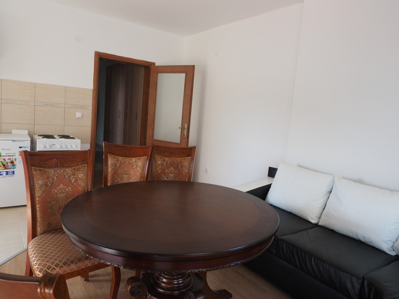 Wohnzimmer mit Essbereich in einer Wohnung, Shushan, Montenegro: runder Tisch, klassische Stühle und schwarzes Sofa.
