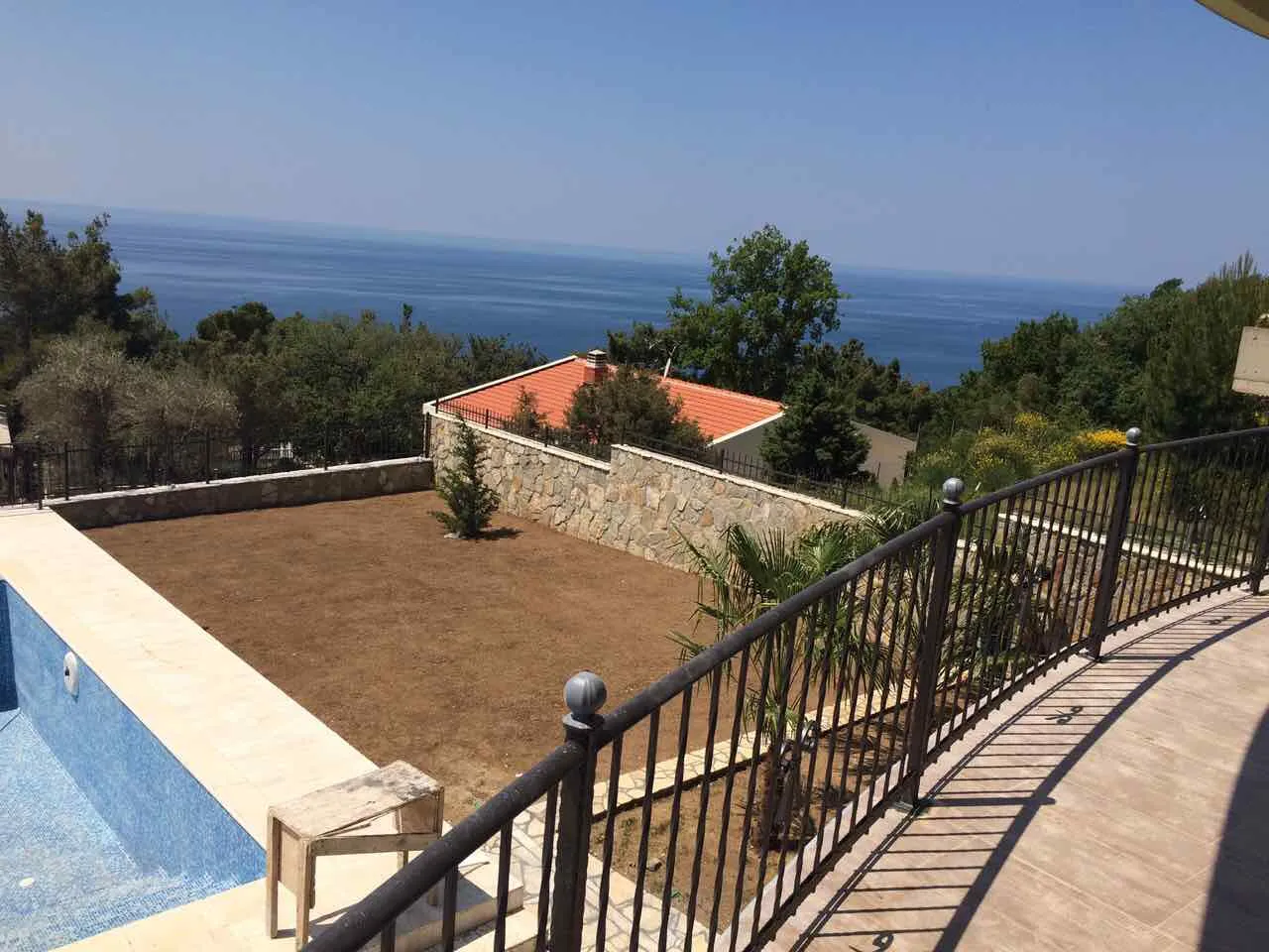 Blick vom Balkon auf einen Innenhof, Garten und das Meer im Hintergrund