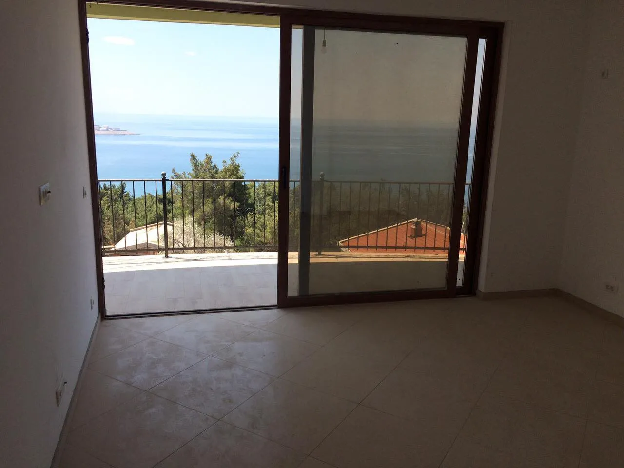 Ein Zimmer mit Schiebetüren aus Glas, die auf einen Balkon mit Meerblick führen.